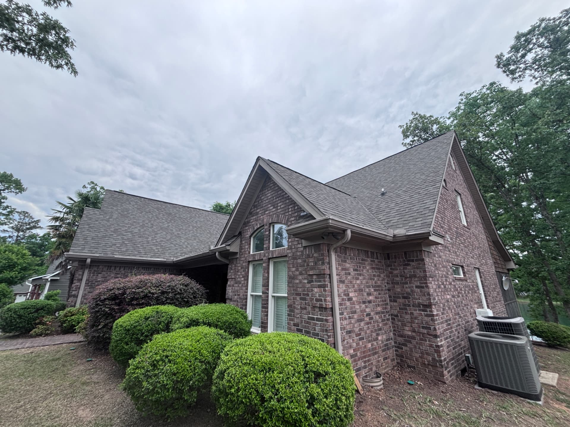 Brick home in Greenwood SC with a new charcoal architectural shingle roof, gutter and downspout installation by Coster Roofing Co