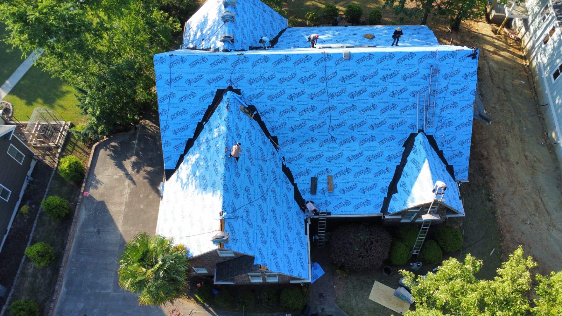 Aerial view of a Coster Roofing crew installing synthetic underlayment during a full roof replacement in Greenwood South Carolina