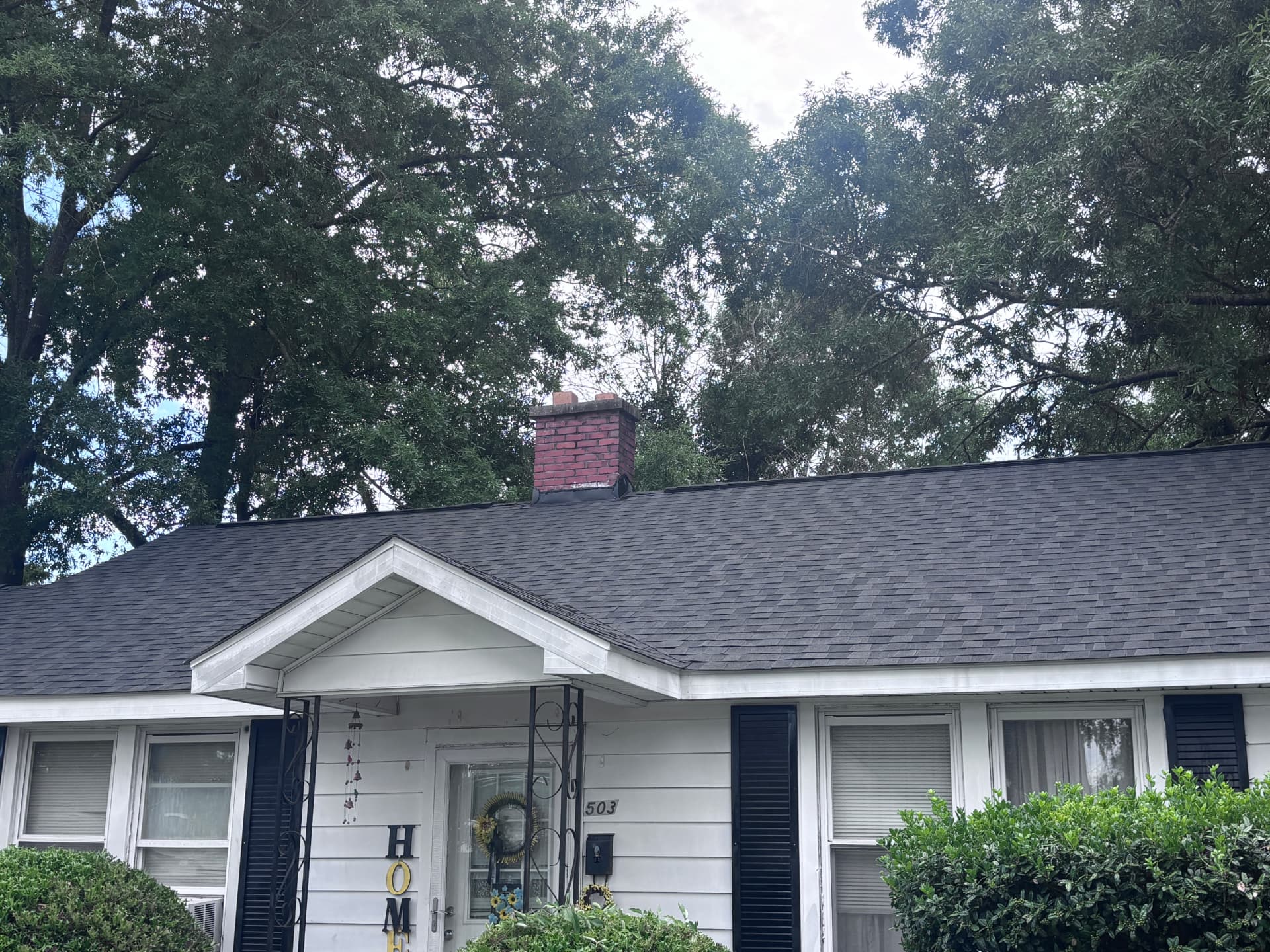 White cottage in Greenwood SC with a new dark asphalt shingle roof installed by Coster Roofing Co