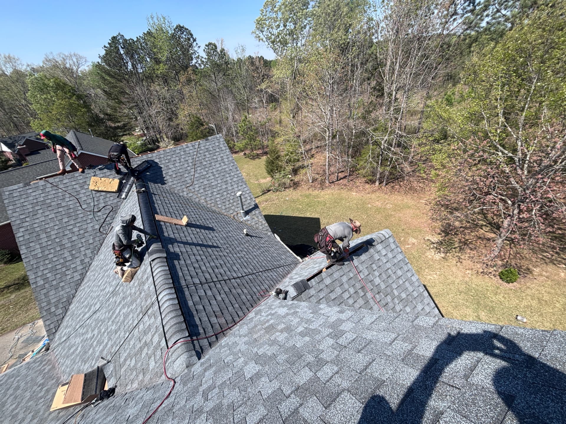 Coster Roofing crew installing gray architectural shingles and ridge cap on a home in Greenwood County SC