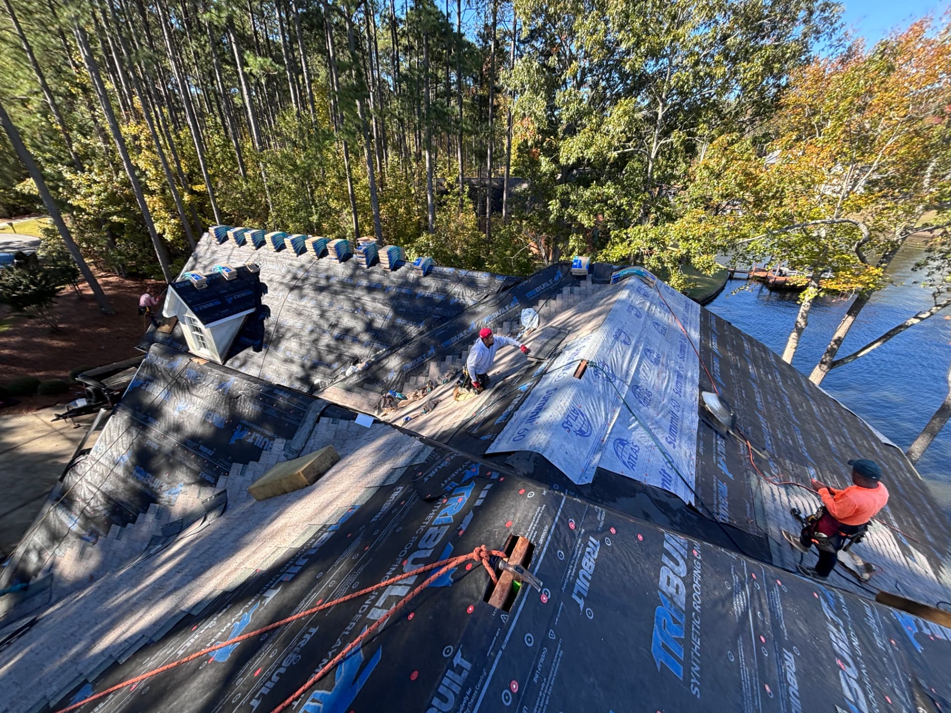 Coster Roofing crew installing synthetic roofing underlayment and architectural shingles on a lakefront home in Greenwood SC